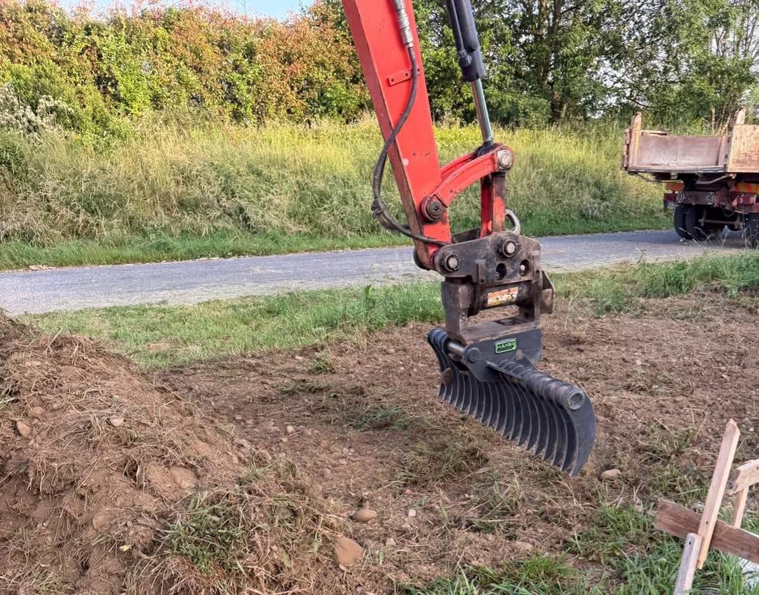 Râteau ramasse-cailloux monté sur mini pelle Kubota U50-5 de 5 tonnes pour le ramassage de pierres et le nettoyage de terrain